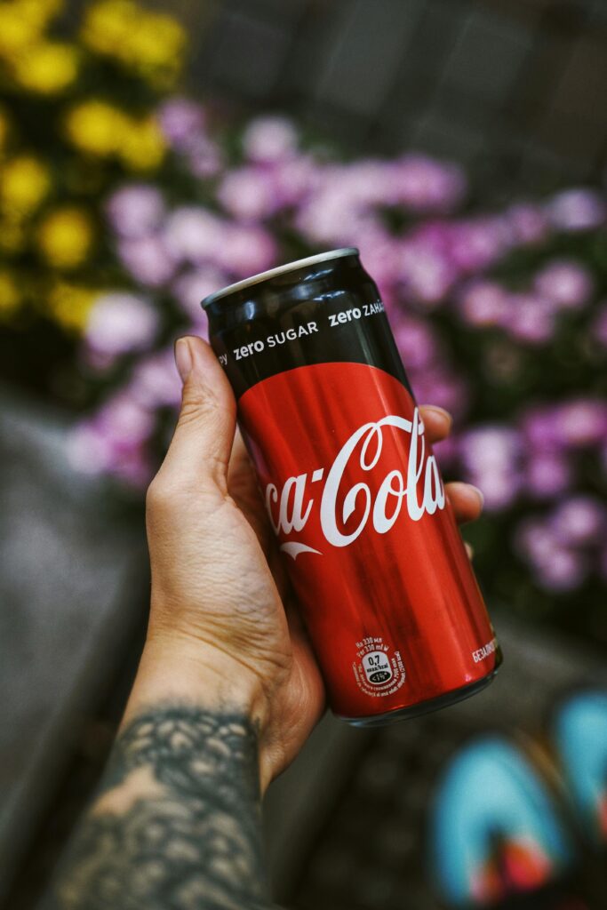 Close-up of a hand holding a Coca-Cola can outdoors in Kyiv's vibrant setting.